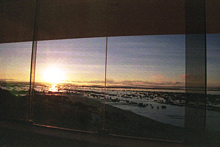 部屋の窓からティティカカ湖に昇る朝陽を見る